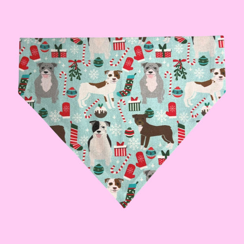 Dog bandana with Christmas-themed design featuring dogs, presents, and candy canes on a light blue background.