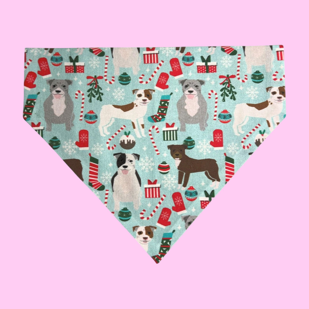 Dog bandana with Christmas-themed design featuring dogs, presents, and candy canes on a light blue background.
